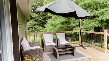 A wooden deck with wicker furniture and a large umbrella.