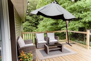 Une terrasse en bois avec des meubles en osier et un grand parasol.