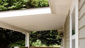 Un porche abrité avec une terrasse en bois, un portail en métal et une pancarte indiquant « Bienvenue ».