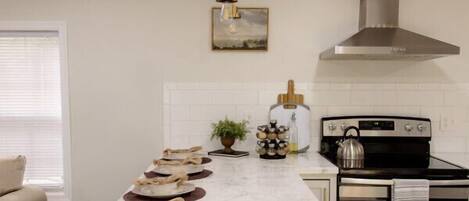 Una cocina moderna con una isla central, electrodomésticos de acero inoxidable y una lámpara colgante.