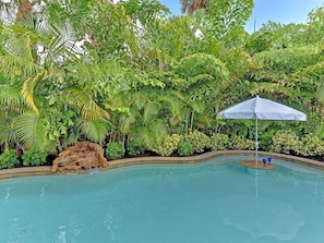 A swimming pool surrounded by lush greenery and a white umbrella. - Salt Shack - Ground Level Private Pool Villa - by Island Real Estate (Holmes Beach)