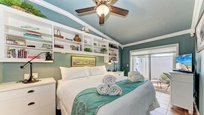 A bedroom with a bed, a ceiling fan, a bookshelf, and a window.