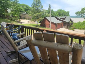 Une terrasse en bois avec des meubles d’extérieur, un chalet rouge et une vue sur une étendue d’eau.