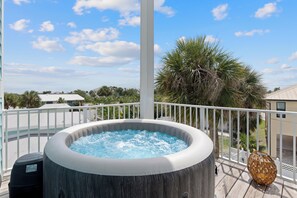 A hot tub on a balcony with a view of palm trees and houses. - Bluewater Vista is a super cool Mid Island Pool Home with Hot Tub (Fort Myers Beach)