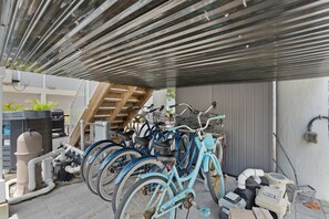 Un espace extérieur abrité où plusieurs vélos sont garés sous un toit en tôle ondulée.