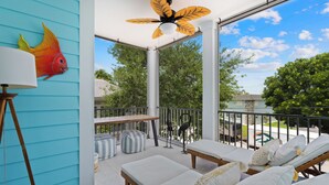 Ein Balkon mit Blick auf Bäume und einen klaren Himmel, ausgestattet mit Liegestühlen und Hocker.