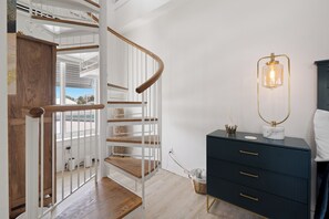 A modern staircase with wooden steps and white railings, leading to an upper floor. - Bluewater Vista is a super cool Mid Island Pool Home with Hot Tub (Fort Myers Beach)