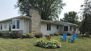 A single-story house with a stone chimney, a front porch, and a well-maintained lawn. - Beautiful spacious house with spectacular  views of Lake Pepin (Lake City)