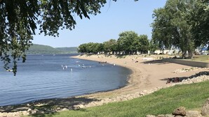 A lakeside beach with a stone wall, grassy areas, and trees. - Beautiful spacious house with spectacular  views of Lake Pepin (Lake City)