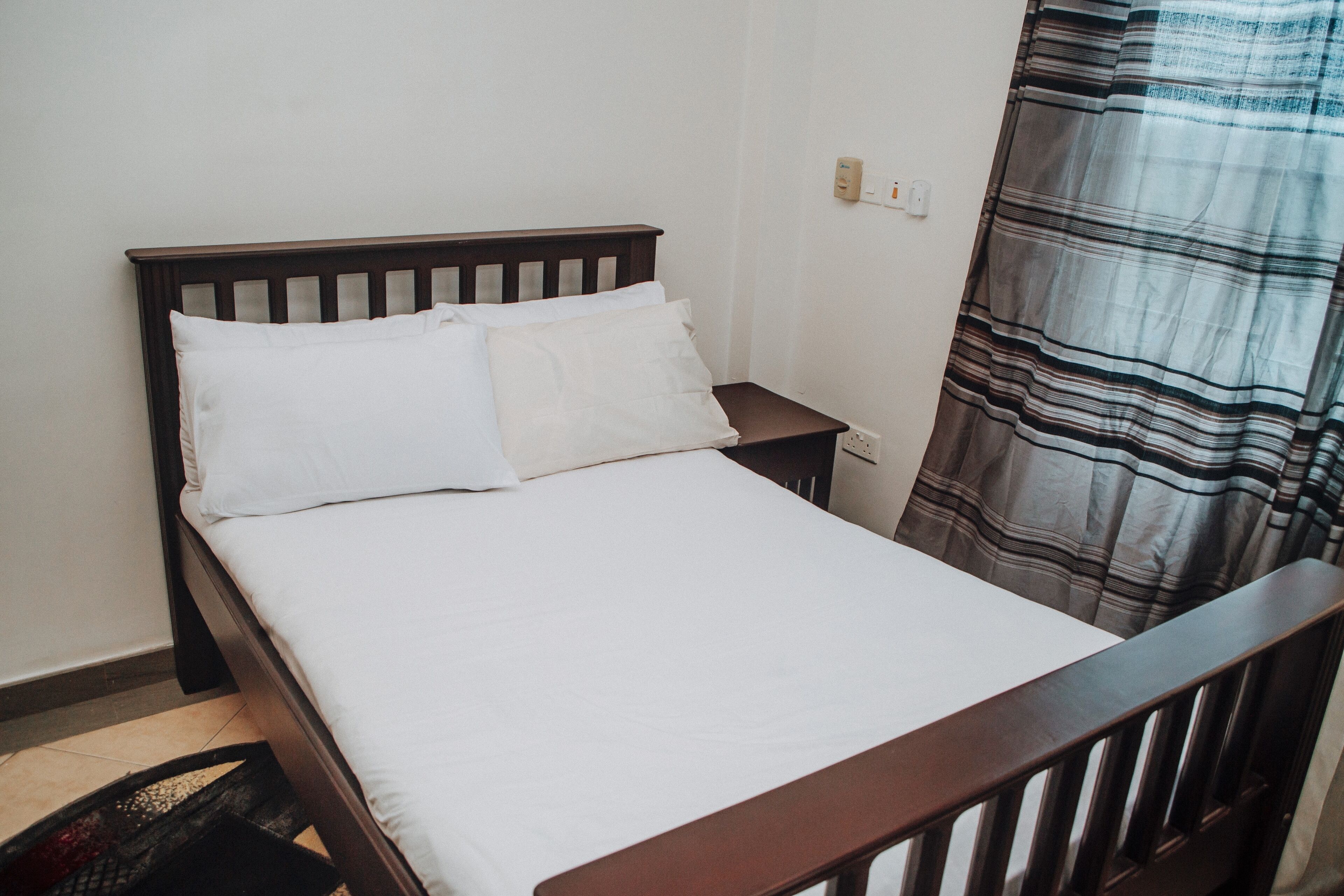 A single bed with white bedding in a room with a wooden headboard and a nightstand.