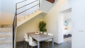A dining area with a table, chairs, a plant, and a staircase.