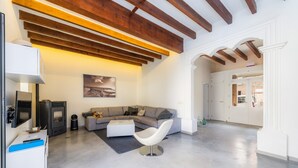 A modern living room with a sofa, a white chair, a fireplace, and a dining area.