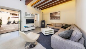 A modern living room with a sofa, a white chair, a flat-screen TV, a coffee table, and a fireplace.