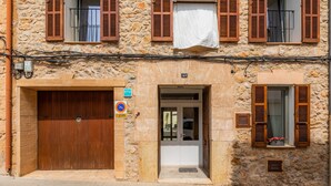 A stone building with a wooden door, a small window with shutters, and a sign indicating no parking.