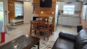 Una sala de estar moderna con una pared de acento de madera, un comedor, una cocina y una zona de estar con un sofá de cuero.