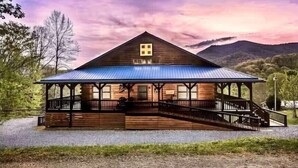 A wooden cabin with a blue roof, a porch, and a staircase leading to the entrance. - Blue Moon Lodge: Reconnect with Family and Friends with Room to Spread Out! (Clyde)