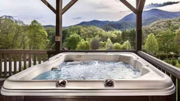 A hot tub on a balcony with a view of a forest and mountains. - Blue Moon Lodge: Reconnect with Family and Friends with Room to Spread Out! (Clyde)