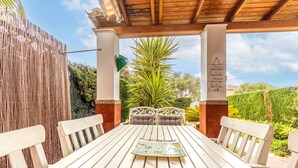 A wooden table with white chairs under a wooden pergola, surrounded by greenery and a clear sky. - Villa Jardin by Interhome (Cambrils)