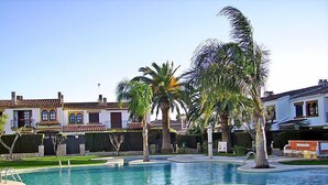 A swimming pool with a surrounding grassy area and palm trees. - Villa Jardin by Interhome (Cambrils)