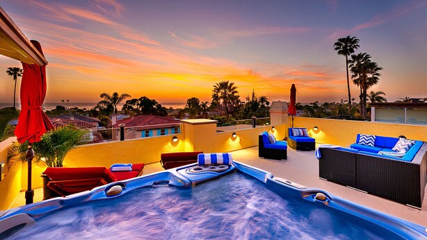 Un espace piscine aménagé sur le toit, avec des chaises longues et un jacuzzi, offrant une vue imprenable sur le coucher de soleil.