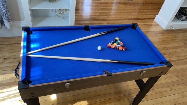 A pool table with two cues, a white cue ball, and a set of colored balls.