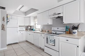 Une cuisine moderne avec des meubles blancs, un four à micro-ondes, une machine à café et une cuisinière.