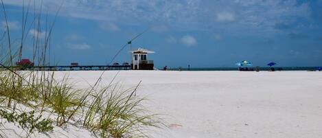 Ein Strand mit einem Rettungsturm, einer Mole und Strandsonnenschirmen.