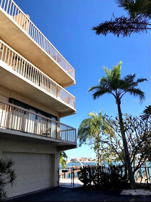 Un immeuble à plusieurs étages doté de balcons, un ciel dégagé et des palmiers.