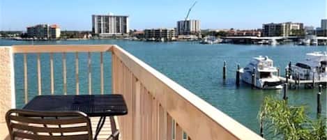 Un balcon avec une table et des chaises donnant sur une marina, avec des bateaux et des bâtiments en arrière-plan.
