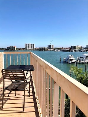 A balcony with a table and chairs overlooking a marina with boats and buildings in the background. - 4 BR Oasis, water views every room steps to beach! (Clearwater)