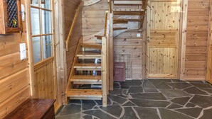 Un interior de madera con piso de piedra, una escalera de madera y una puerta.