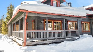 Una casa de madera con un porche cubierto de nieve.