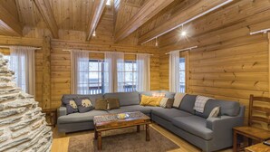Interior acogedor de una cabaña de madera con un sofá seccional, una mesa de centro y una pared de piedra.