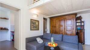 A living room with a grey sofa, a wooden cabinet, and a fruit bowl on a coffee table. - Apartment "Garden Vista Lago" in Como with Lake View, Wi-Fi & Private Garden (Como)