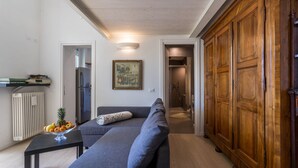 A modern living room with a sofa, a wooden wardrobe, a radiator, and a framed picture on the wall. - Apartment "Garden Vista Lago" in Como with Lake View, Wi-Fi & Private Garden (Como)