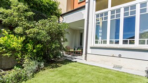 A residential building with a well-maintained lawn, a patio with outdoor furniture, and a large window. - Apartment "Garden Vista Lago" in Como with Lake View, Wi-Fi & Private Garden (Como)