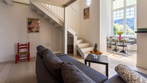 A modern living room with a staircase, a dining area, and a view of the outdoors. - Apartment "Garden Vista Lago" in Como with Lake View, Wi-Fi & Private Garden (Como)