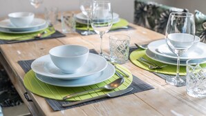 A dining table set with plates, bowls, glasses, and cutlery, with green placemats and a wooden table surface. - Vacation Apartment "Central Vista Lago" with Lake View & Private Terrace (Como)