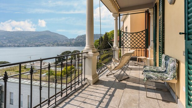 A balcony with a view of a lake, a chair, and a sofa. - Vacation Apartment "Central Vista Lago" with Lake View & Private Terrace (Como)