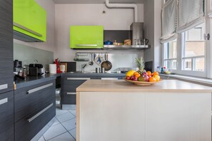 A modern kitchen with grey cabinets, a wooden island, and a fruit bowl.