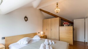 Un lit bien fait, avec des serviettes pliées, une tête de lit en bois, une table de chevet avec une lampe et une armoire avec un miroir.