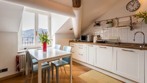 Une cuisine avec des armoires blanches, un plan de travail en bois, un four à micro-ondes et une horloge.