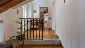 Un escalier avec une rampe en bois, une plante en pot et un luminaire fixé au mur.