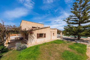 Un bâtiment en pierre doté d’une terrasse, d’un grand arbre et surplombant un ciel dégagé.