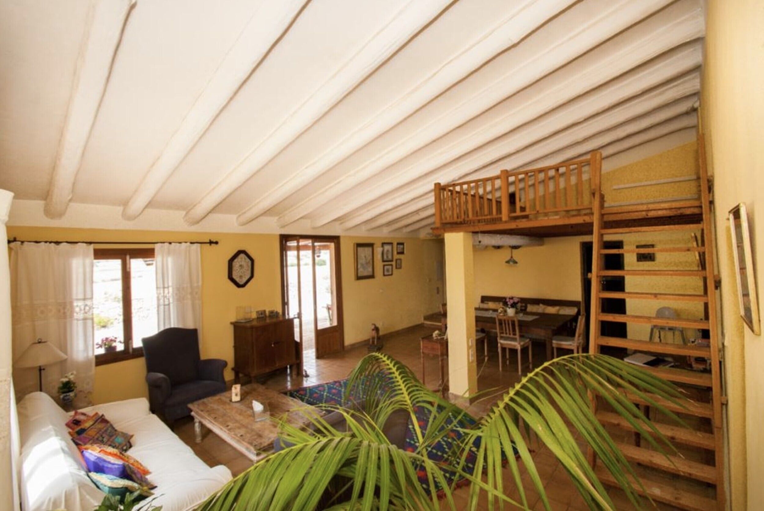 A room with a bunk bed, a sofa, a coffee table, a chair, and a lamp.