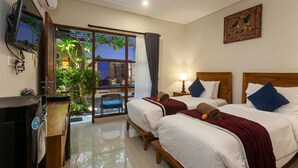 A hotel room with two beds, a TV, and a balcony with plants. - Naksa Homestay Sanur (Denpasar)