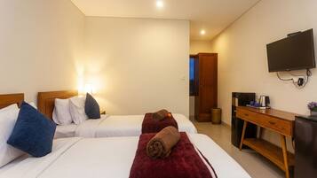 Una habitación de hotel con dos camas, televisión, escritorio y un cesto de basura.