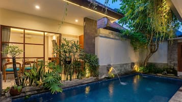 Una piscina al aire libre, sombrillas, sillones reclinables de piscina