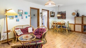 A cozy living room with wicker furniture, a dining area with a wooden table and chairs, and a ceiling light fixture. - Vacation home Měřín by Interhome (Slapy)