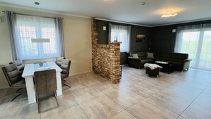 Ampla sala de estar com mesa e cadeiras de jantar, um sofá e uma mesa de centro.